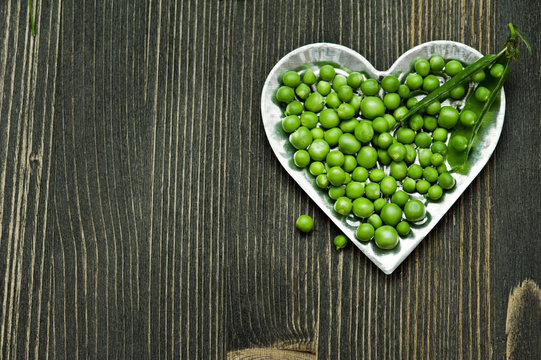 Green peas in bowl on dark wooden background