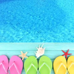Colored flip flops on wooden platform beside sea