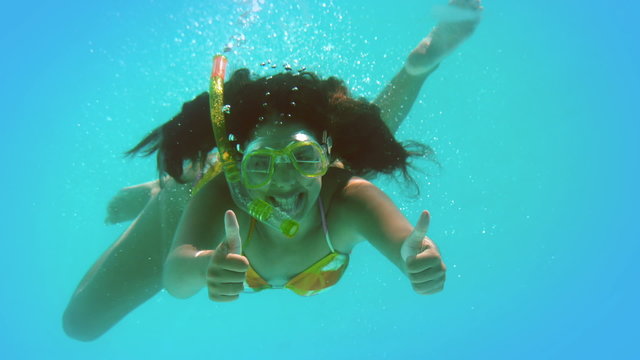 Happy brunette wearing snorkel underwater showing thumbs up