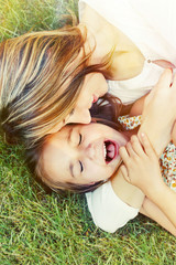 happy little girl and her mother having fun outdoors on the gras