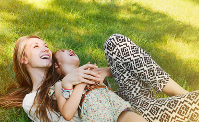 happy little girl and her mother having fun on the grass in sunn