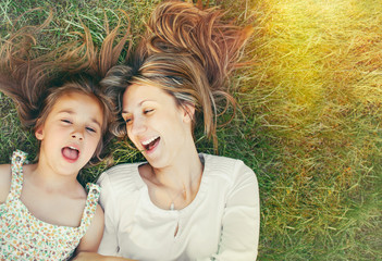 cute little girl and her mother having fun on the grass in sunny