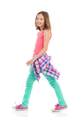 Cheerful teen girl walking, side view.