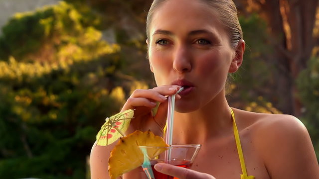 Sexy blonde drinking cocktail in yellow bikini