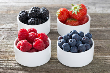 raspberries, blueberries, blackberries and strawberries in bowls