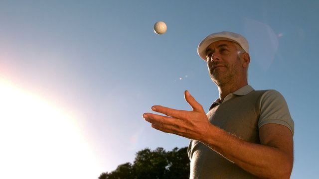Golfer throwing and catching golf ball on the course