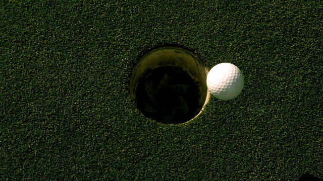 Golf ball rolling into the hole on putting green