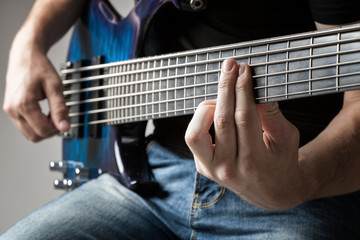 male musician playing on six-string bass guitar