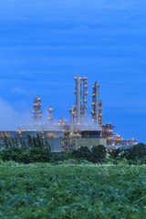 Fototapeta na wymiar Refinery factory with green field on twilight
