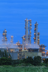 Refinery factory with green field on twilight