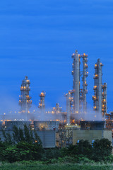 Refinery factory with green field on twilight