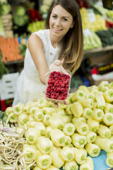 Young woman buying raspberries at the market