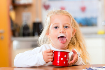 Mädchen trinkt Milch in der Küche