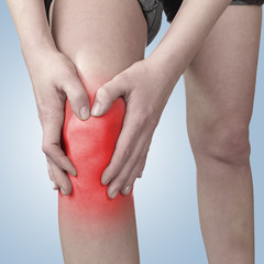 Acute pain in a knee. Female holding hand to spot of knee-aches.