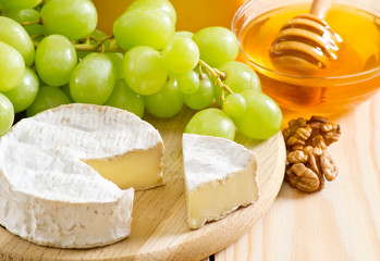 Still life of cheese, honey, walnuts and grapes