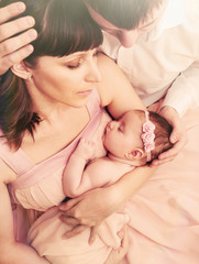 Obraz na płótnie Canvas caring loving parents holding cute sleeping little baby girl wit