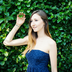 Young woman portrait with natural green hedge background.