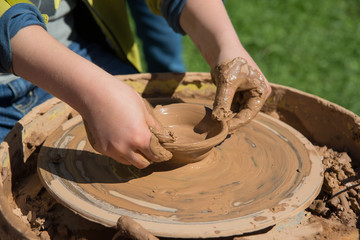 Children outdoor studying using pottery wheel