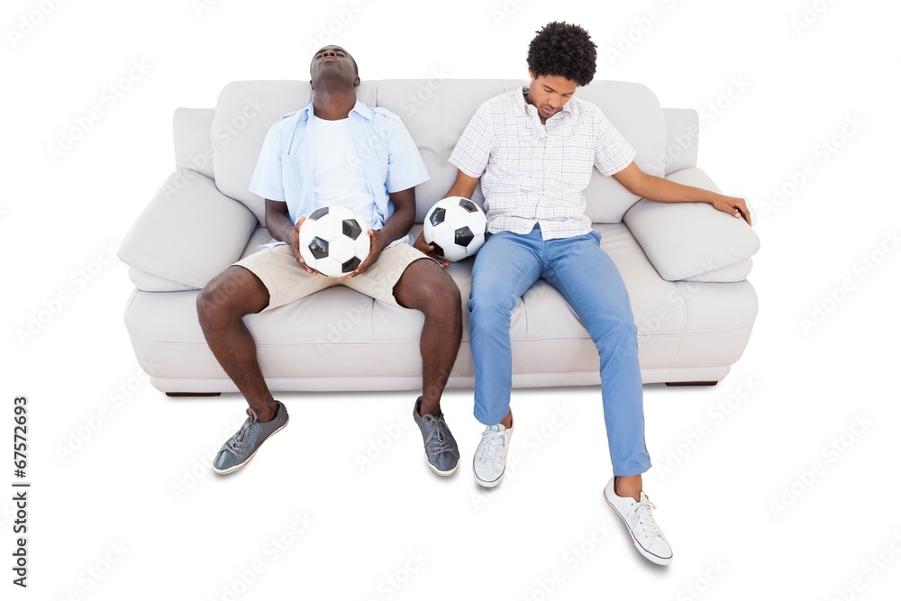 Wall mural Distraught football fans sitting on the couch with balls