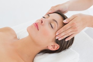 Obraz na płótnie Canvas Attractive young woman receiving head massage at spa center