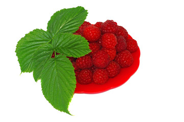 Ripe raspberries decorated with green leaf in a small platter