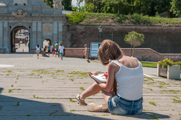 Student sitting on the ground and sketching