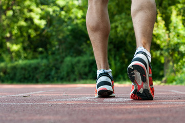 Fototapeta na wymiar Muscular athlete legs waiting at the starting line on track