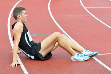 Young athlete sitting on the ground after running race