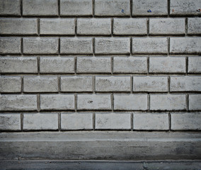 Grey wall from blocks with a strip of asphalt.