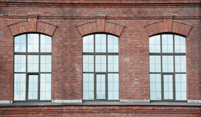 Three window on a red bric wall