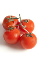 Four cherry tomatoes on a white background - Selective focus.