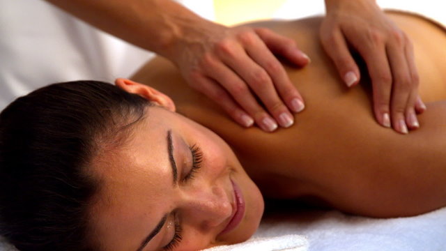 Smiling brunette enjoying a massage at the spa