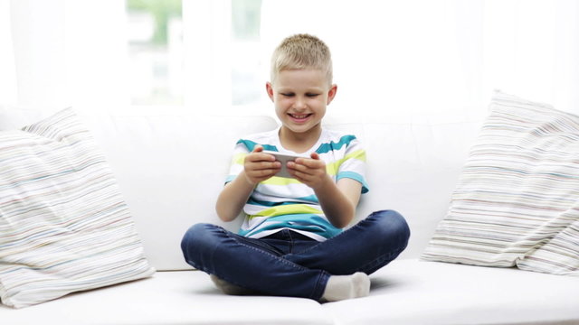 smiling boy playing with smartphone at home
