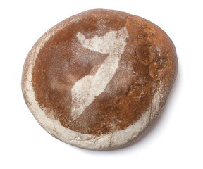 A loaf of fresh bread covered with rye flour in the shape of Som