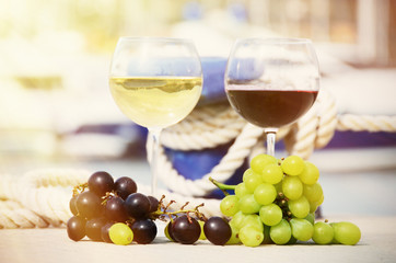 Pair of wineglasses and grapes against yachts in La Spezia, Ital