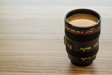 Filtered Coffee in a Lens Body on Brown Background with Copy Space