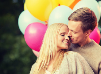 couple with colorful balloons kissing in the park