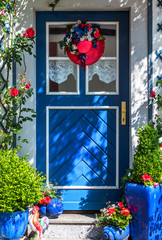 Fototapeta na wymiar Blaue Haustür geschmückt mit rotem Hut