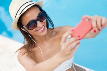 Naklejka premium Beautiful girl taking a selfie at the swimming pool.