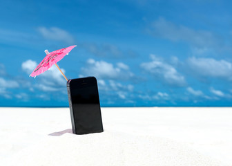 Mobile phone and cocktail umbrella on the beach