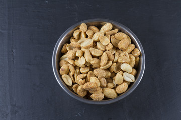 Dry roasted peanuts in metal bowl  on slate.