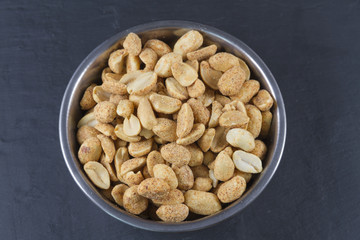 Dry roasted peanuts in metal bowl  on slate.