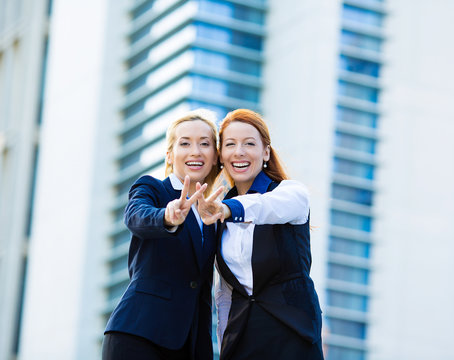 Two excited business women show victory sign win gesture