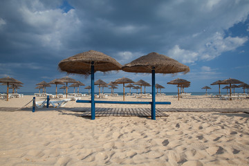 Different parasols and sun loungers on the empty beach on Tavira