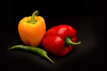 Sweet and chilli pepper on black background