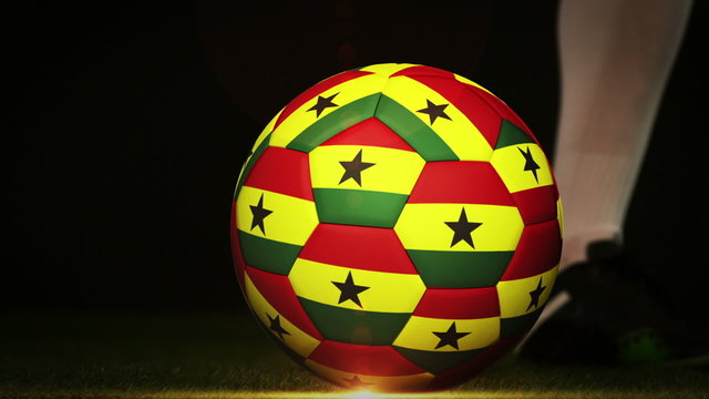 Football player kicking ghana flag ball