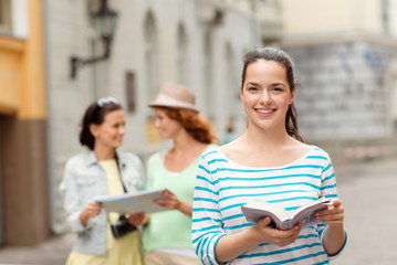 smiling teenage girls with city guides and camera