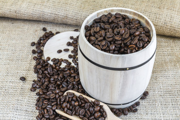 scattered roasted coffee beans around a wooden barrel