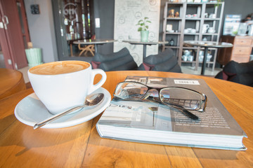Coffee cup with glassware on book on table