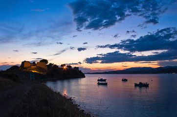 Sunset at Toroni bay with old roman fortress and fishing boats - obrazy, fototapety, plakaty